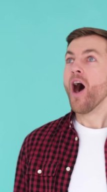 Şok olmuş Avrupalı, vay canına diyor. Mavi arka planda yakışıklı bir adam izlenim gösterir. Dikey video