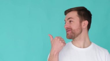 Mutlu genç adam coşkuyla gülümsüyor ve kameraya bakıyor. Stüdyonun mavi arka planında büyük bir izole olduğunu söylüyor..