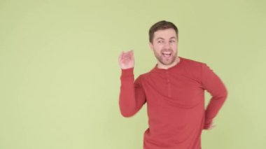 Turuncu kazaklı genç bir adam stüdyonun arka planında garip bir şekilde dans ediyor. Dikey video