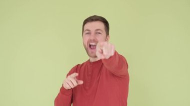 Stüdyo arka planında dans eden mutlu Avustralyalı adam. Yeşil arka plandaki yakışıklı bir adam tatmin olmuş duygularını ifade eder. Dikey video