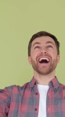 Duyduklarına inanamayan genç adam elini kaldırıyor, şok olmuş adam. Stüdyonun arka planındaki video. Dikey video