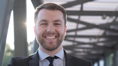 Güneşli bir günde kameraya gülümseyen sakallı bir iş adamının portresi. Adam bir yönetici. Dikey video