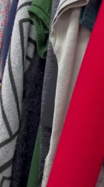 İkinci el giysileri inceleyen bir kadının yakın çekimi. Kullanılmış giysiler almak. Dikey video.