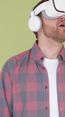 Stüdyoda sanal gerçeklik gözlüğü takan sakallı adam. VR kulaklıklı bir akıllı telefon kullanmak. Modern teknoloji. Dikey video
