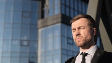 Orta yaşlı bir iş adamının portresi güneş ışığının arka planında caddede duruyor. Ofis çalışanı