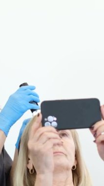 Doktor saç yapısına teşhis koyuyor. Yaşlı bir kadının trikoloğa danışması. Dikey video