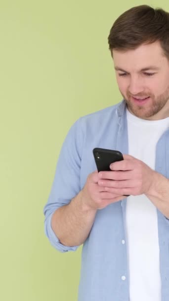 Mladý Muž Pomocí Mobilního Telefonu Vypadá Šťastně Vesele Zeleném Pozadí — Stock video