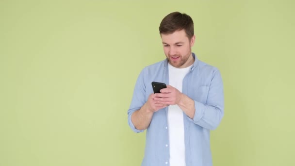 Cep Telefonunu Kullanan Genç Adam Yeşil Arka Planda Mutlu Mutlu — Stok video