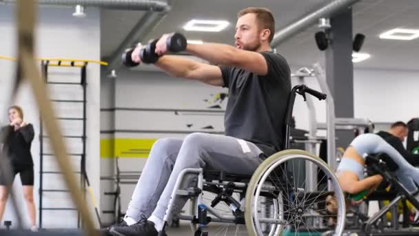 他是坐轮椅的残疾人 他在体育馆里举起哑铃 体育克服概念 垂直录像 — 图库视频影像