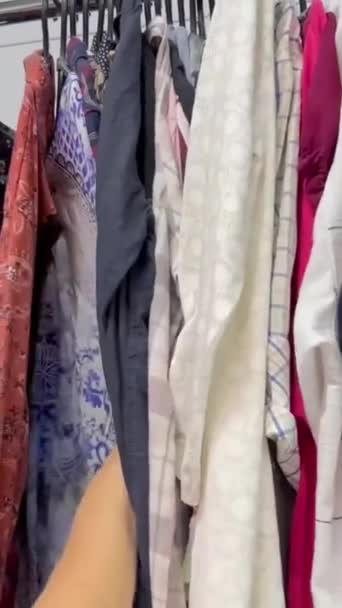 Kobieta Wybiera Ubrania Sklepie Używanymi Rzeczami Kupuję Używane Ubrania Kręcenie — Wideo stockowe