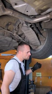 Araba şasisini tamir eden bir araba tamircisinin dikey videosu. Araba tamiri kavramı. Dikey video.