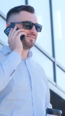 Yönetmen cam ofisin yanında dururken bir telefon görüşmesi yapar. Kendine güvenen sakallı yönetici telefonda konuşuyor. Dikey video