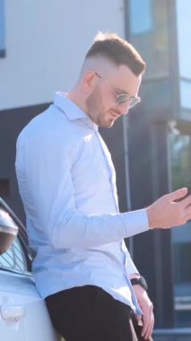 Genç bir iş adamı bir iş merkezinin arka planında akıllı telefon kullanır. Dikey video.