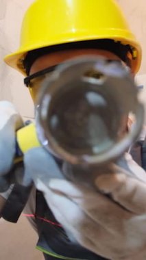 Bir inşaat işçisi kameraya bakarken elektrikli matkap kullanır. Ev yenileme konsepti. Dikey video