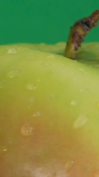 水中の美しいリンゴは緑色の背景に落ちています マクロビデオ バーティカルビデオ — ストック動画