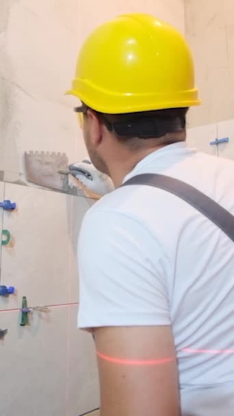 用工具和粘合剂把瓷砖铺在墙上 工人修理工 建筑工人 安装瓷砖 垂直录像 — 图库视频影像