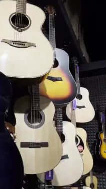 Bir müzik enstrümanı mağazasında akustik gitarlar. Çok renkli güzel gitarlar. Dizili müzik aletleri konsepti. Dikey video