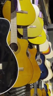 Bir enstrüman dükkanında sergilenen klasik gitarlar. Müzik aletlerinde indirim var. Dikey video