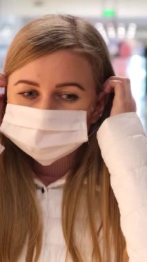 Sarışın kadın markette tıbbi maske takıyor ve Coronavirus 'a karşı korumak için kameraya bakıyor. Koronavirüs hastalığı tehlikesi COVID-19