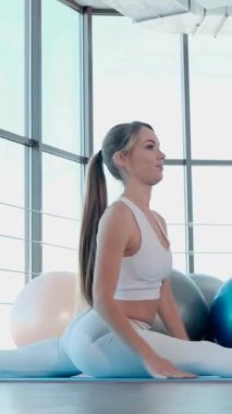 Atletik kız vücudu rahatlatmak için yoga egzersizleri yapıyor. Yoga koçu. Dikey video