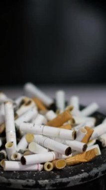 The man throws the cigarette butt into the ashtray. Bad habits, smoking, lots of smoked cigarettes. Vertical video