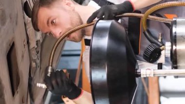 Araba tamircisi modern bir arabanın motorunun yağını değiştiriyor. Arabaların profesyonel onarımı ve bakımı. Dikey video
