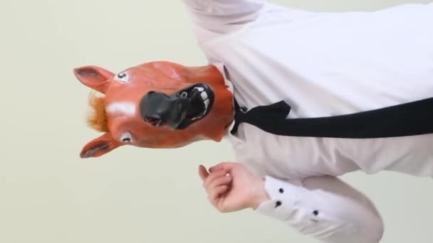 スタジオのバックグラウンドで馬の仮面の男が踊る 男が演じる面白いダンス スローモーション バーティカルビデオ — ストック動画