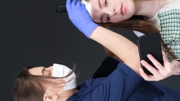 ヘアトリコプトの手順 コンピュータ トリコプト トリコロジストは 診療所でトリコスコープを有する患者の髪を調べます バーティカルビデオ — ストック動画