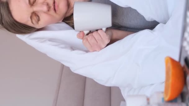 Sarsを持っている若い女性の肖像画と温かいお茶を飲む 自宅での孤立 風邪の自己治療について バーティカルビデオ — ストック動画