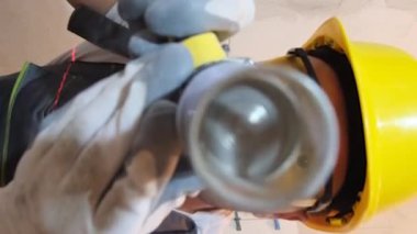 Özel üniformalı bir inşaat işçisinin miksaj aletini tuttuğu yakın plan. İnşaat mikseri. Tatbikat. Seramik fayans yükleyici. Dikey video