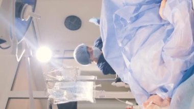 Cerrahlar varisli yaşlı bir kadının bacaklarını ameliyat ederler. Cerrahların çalışma süreci. Dikey video