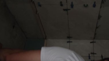 Profesyonel bir usta, seramik fayansları lazer cetvelle banyoya yerleştirir. Döşemeleri doğru döşemişler. Dikey video