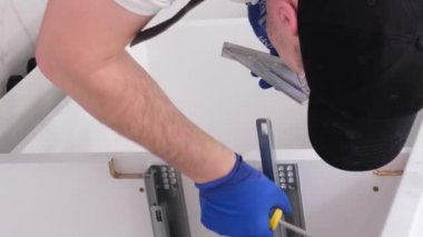 Erkek eli mekanizmayı ayarlıyor. Tamirci mutfakta dolap menteşesini tamir ediyor. Dikey video