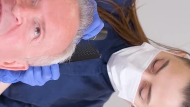 一位老年病专家正在对老年人进行检查 头发护理的概念 垂直录像 — 图库视频影像