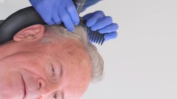 年配の男性がトリコロジストによって検査を受けている 老後の脱毛の問題について バーティカルビデオ — ストック動画