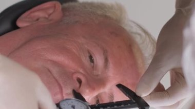 Doktor cerrahın portresi erkek yüzünde iz bırakıyor, yaşlı adam. Dikey video.