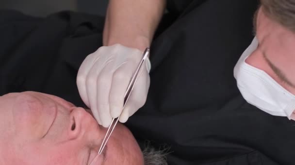 Seorang Ahli Bedah Memeriksa Wajah Seorang Pria Tua Sebelum Operasi — Stok Video