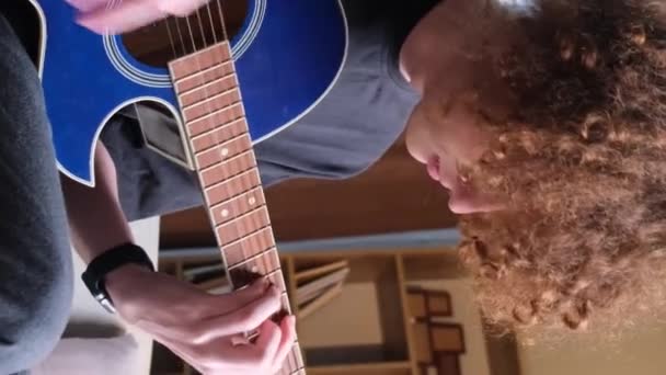一个年轻的卷曲红头发的家伙正在学习弹吉他 才华横溢的吉他手弹奏着镇定的旋律 Hobby 垂直录像 — 图库视频影像