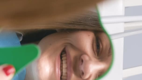 在牙科诊所里欣赏微笑的女人 快乐的年轻女性微笑着检查她完美的牙齿健康在镜子里的特写 垂直录像 — 图库视频影像