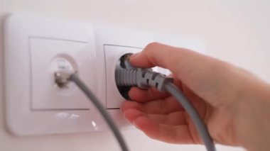 Bir kadının eli uzatma kablosunu çıkarır. Evde elektrikli aletlerin kullanımı.
