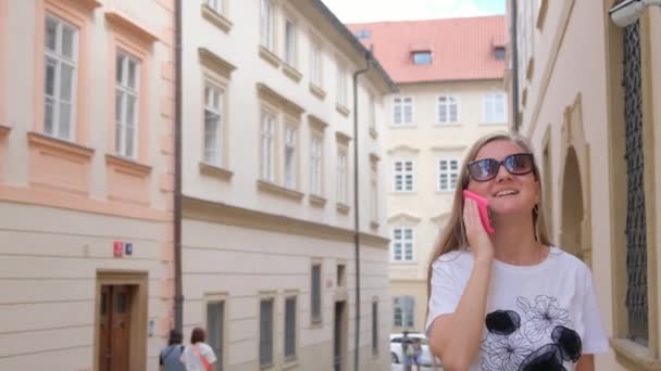 在一个阳光明媚的日子里 一位女士一边走在捷克共和国布拉格的大街上一边用智能手机说话 — 图库视频影像