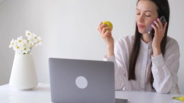 İş kadını bilgisayarın başında çalışıyor ve sarı sağlıklı bir elma yiyor. İşte sağlıklı bir atıştırmalık. Bir şeyler atıştır.