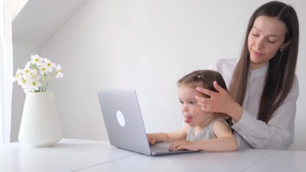 現代的な白い壁の背景を持つ部屋のコンピュータで小さな娘を持つ若い女性 働く母と小さな女の子 — ストック動画