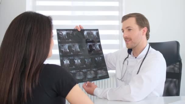 一个妇女在医生预约 穿着制服的专业医生展示了X光图像 建立一个诊断 及时治疗疾病 — 图库视频影像