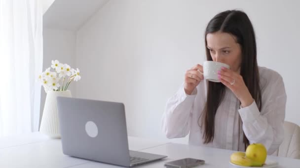 白人のビジネス服を着た働く若い女性は コンピュータで働き お茶やコーヒーを飲みます コーヒーブレイク 仕事のための簡単なスナック 自宅からリモートで作業 — ストック動画