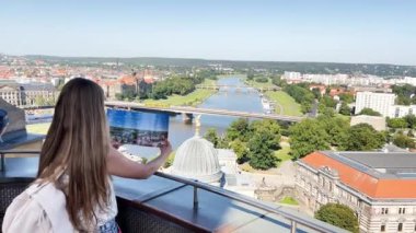 Bir turist Dresden şehrinin haritasını tutuyor ve manzaraya tepeden bakıyor. Avrupa 'da turizm ve seyahat