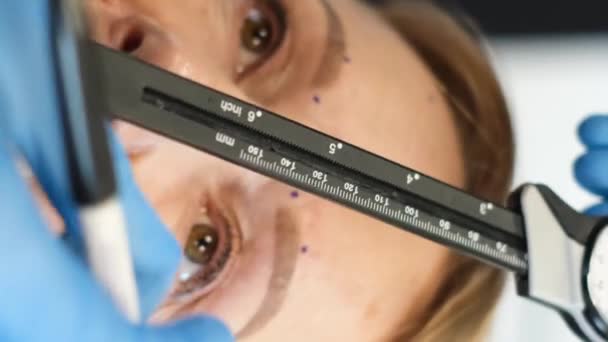 在一名整形外科医生对一名退休妇女进行检查的特写镜头下 他使用了口径手枪 老年面部整形手术的概念 垂直录像 — 图库视频影像