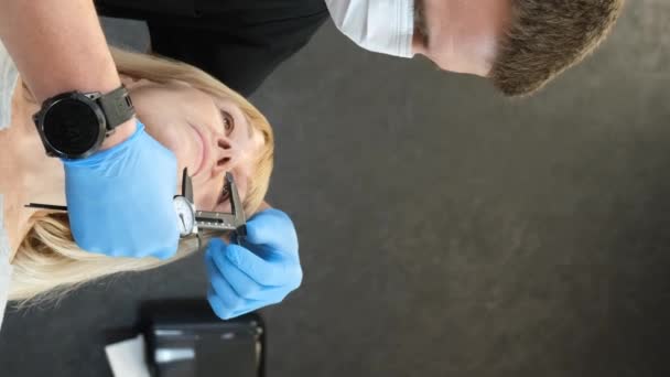 医師は 顔に手術用の高齢女性を準備しています プラスチック手術前に顔に穴を開けます フェイシャルプラスチック手術のコンセプト バーティカルビデオ — ストック動画