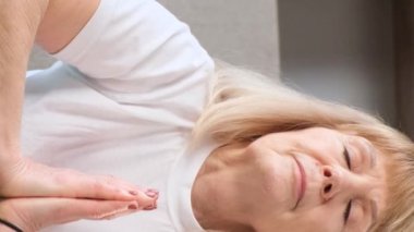 Yoga yapan yaşlı, sarışın bir kadının portresi. Meditasyon. Kendinle uyum içinde. Dikey video