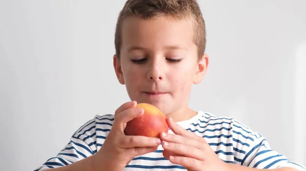 A little boy eats a delicious ripe peach. Delicious organically pure fruits. 4k video
